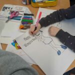 Uczennice wspólnie kolorują obrazek na lekcji kulturowej.