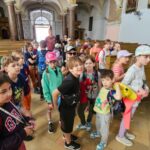 Grupa uczniów zwiedza zabytkowy kościół.