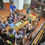 Grupa uczniów zwiedza Muzeum Papiernictwa.