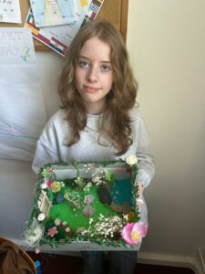 Uczennica prezentuje własnoręcznie wykonaną makietę ogrodu, inspirowaną lekturą "Tajemniczy ogród".