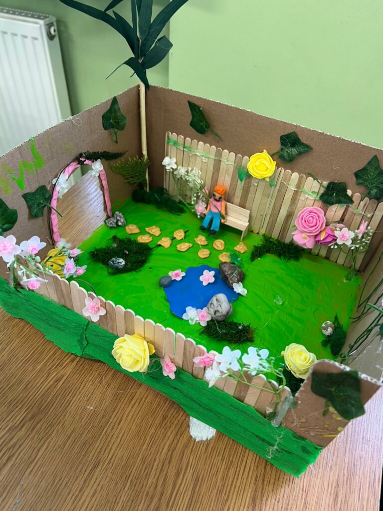 Zbliżenie na ręcznie wykonaną makietę ogrodu inspirowaną lekturą "Tajemniczy ogród" Francesa Hodgson Burnetta.