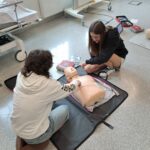 Uczennica wykonuje masaż serca na manekinie.