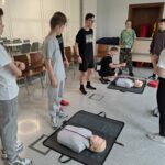 Uczniowie stojący przed manekinami medycznymi.