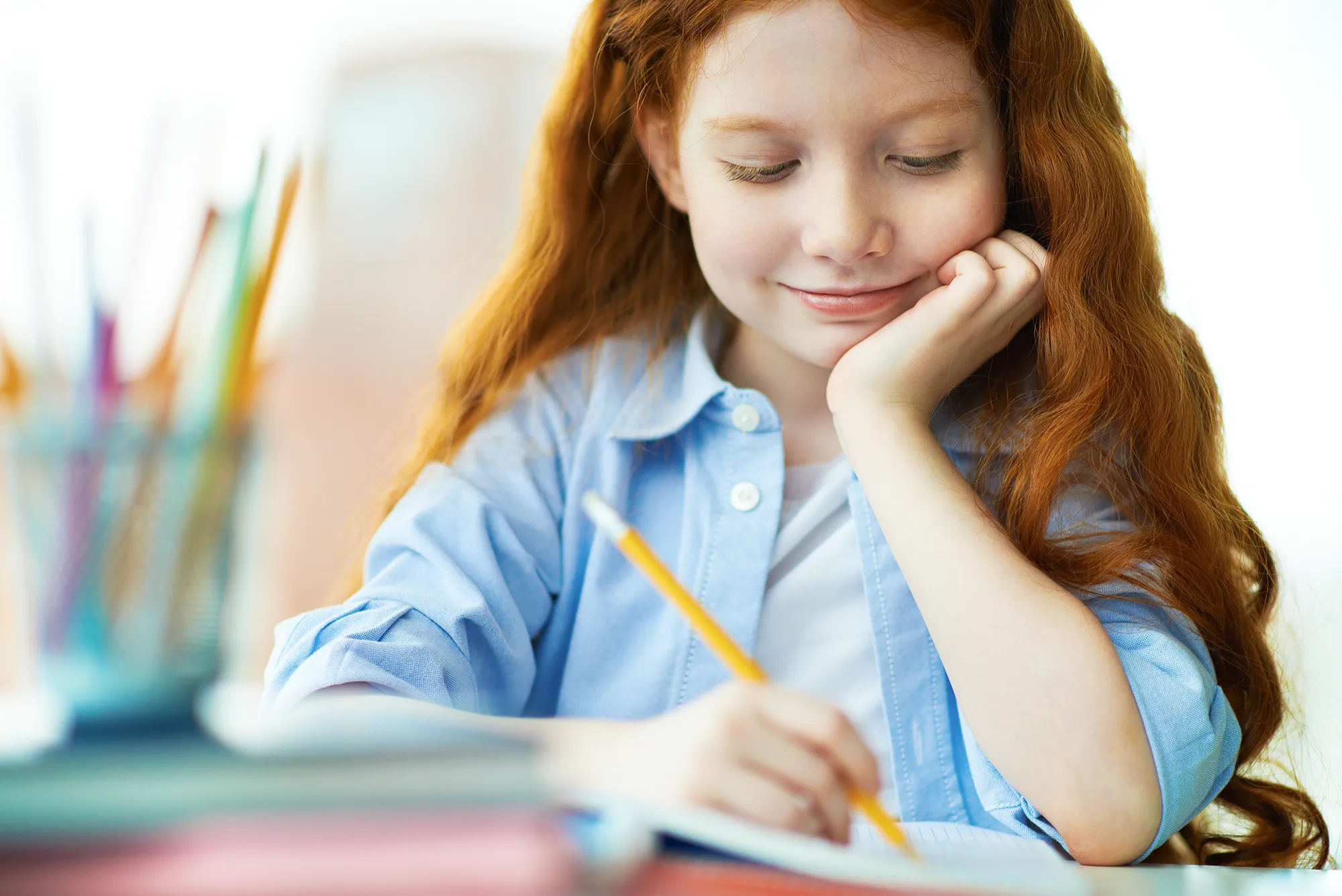 Uśmiechnięta dziewczynka wykonująca zadanie podczas zajęć po zmianie szkoły podstawowej